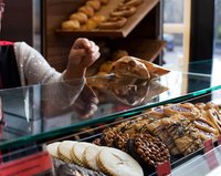 Bäckereifachverkäuferin bedient Kund:in und nimmt Geld entegegen.